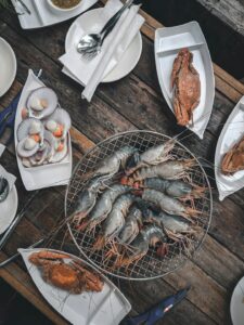 Lightly coated shrimp, oysters, and fish served with hushpuppies, coleslaw, and fries on a casual table.