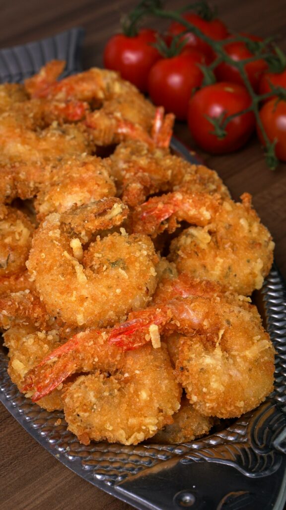 Golden lightly breaded shrimp with lemon wedges, hush puppies, and dipping sauces on a casual seafood platter.